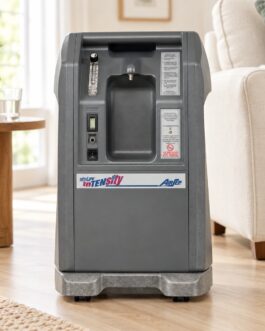 AirSep NewLife Intensity 10L oxygen concentrator beside an armchair in a bright home setting.